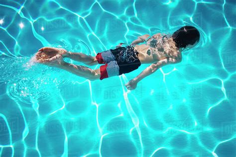 Boy swimming in blue swimming pool - Stock Photo - Dissolve