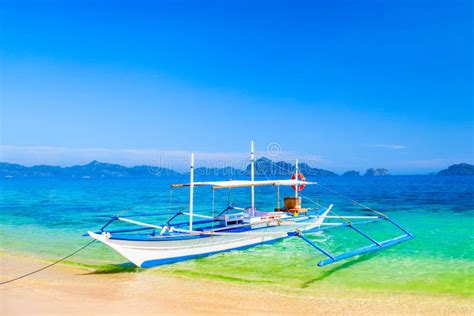 Bangka Banca Boat on Sandy Remote Beach Lit by Golden Sunset Light. El Nido Village in ...