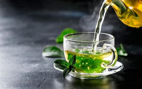 Premium Photo | Hot chinese green tea with mint with splash pouring from the kettle into the cup ...