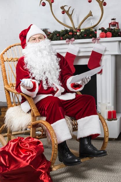 Free Photo | Santa sitting in rocking chair with wishlist