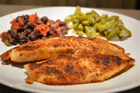 a white plate topped with chicken, beans and green beans next to a side ...