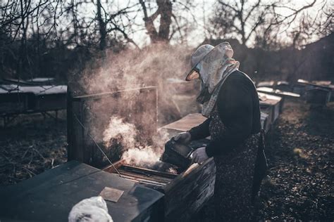 Premium Photo | The beekeeper opens the hive and smokes them