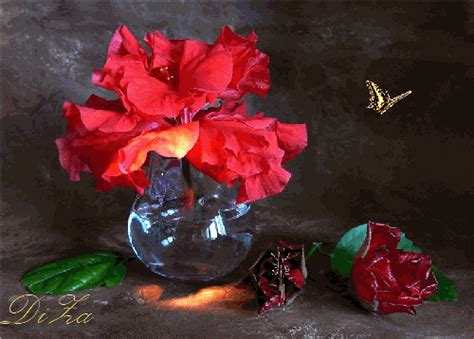 a glass vase filled with red flowers on top of a table next to a butterfly