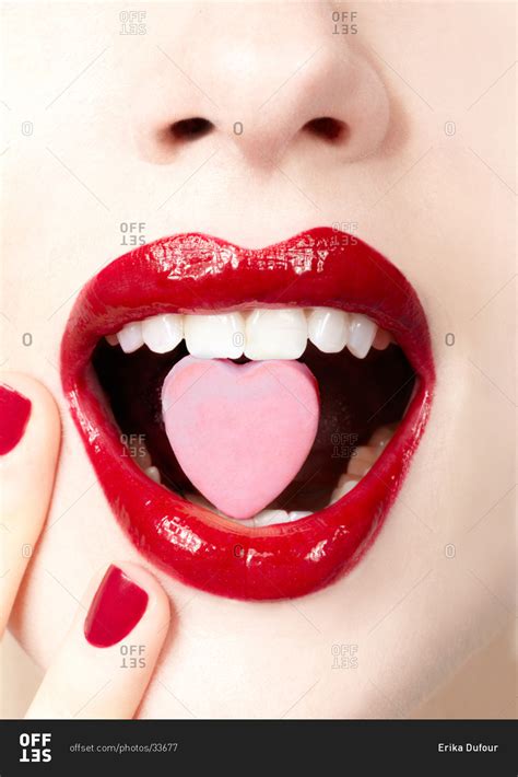 Close-up of a woman's lips and mouth with a heart-shaped candy between ...