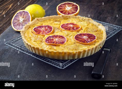 Traditional French tart au citron with blood orange slices served as close-up in a backing form ...