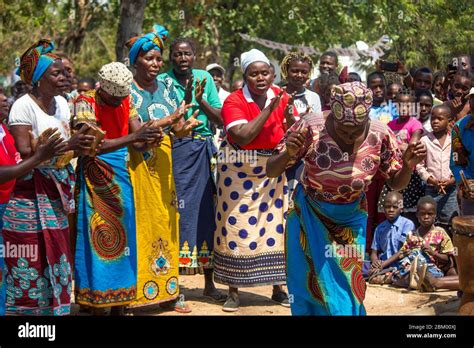 Women dancing and singing dressed in colorful traditional African fabrics known as capulana in ...