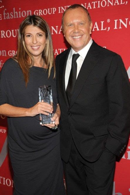 a man and woman standing next to each other in front of a red wall ...