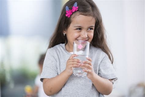 Smiling cute girl holding glass of water at home - Southeast Health District