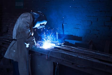 Man Wearing Welding Helmet Welding Metal Near Gray Brick Wall · Free Stock Photo