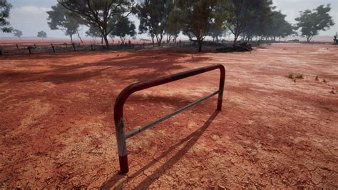 A rustic red dirt field with a charming fence and trees in the ...