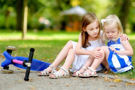 Girl comforting her sister after she fell Stock Photo by ©MNStudio 100831652