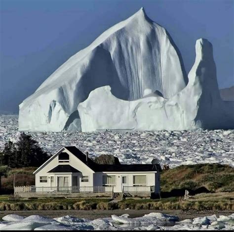 Giant iceberg floating in the Atlantic Ocean near a house in Newfoundland, Canada | MATTHEW'S ISLAND