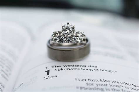 Royalty-Free photo: Silver-colored band ring on top of white book with The Wedding Day song ...