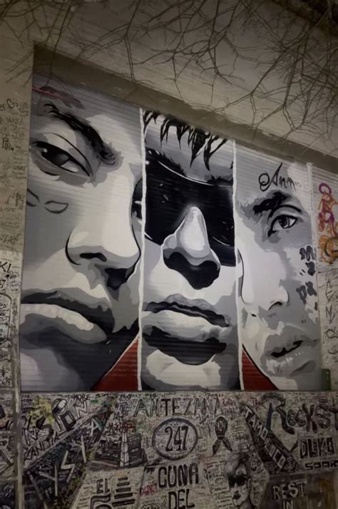 a wall covered in graffiti and pictures of men's faces, with words written all over it