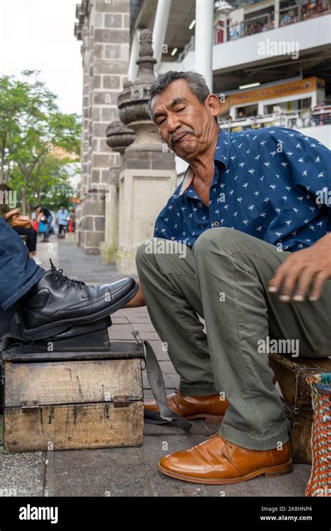 older latino man, dark skinned, cleaning and shining shoes, happy with ...