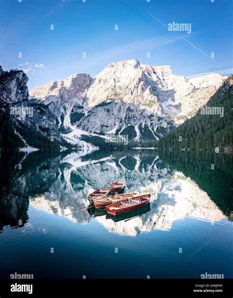 Boats moored in Lake Braies (Pragser Wildsee) with mountains reflected in water at sunrise ...