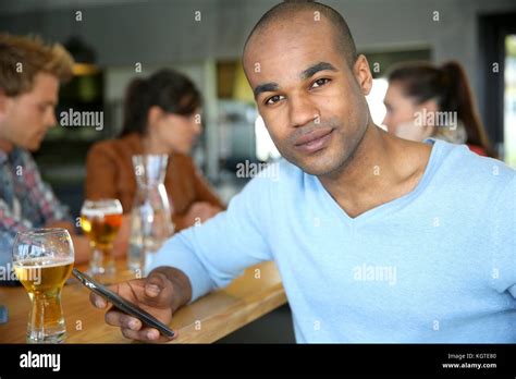 Man sitting at snack bar table checking messages Stock Photo - Alamy