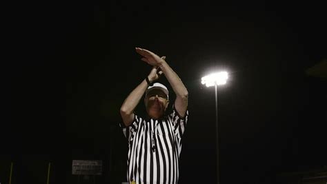 A Football Referee Makes A Personal Foul Penalty Hand Gesture In Front Of Large Bright Stadium ...