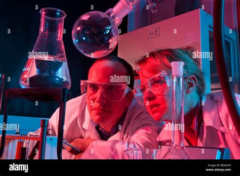 Woman and man in lab coats with lab equipment red and blue light Stock Photo - Alamy