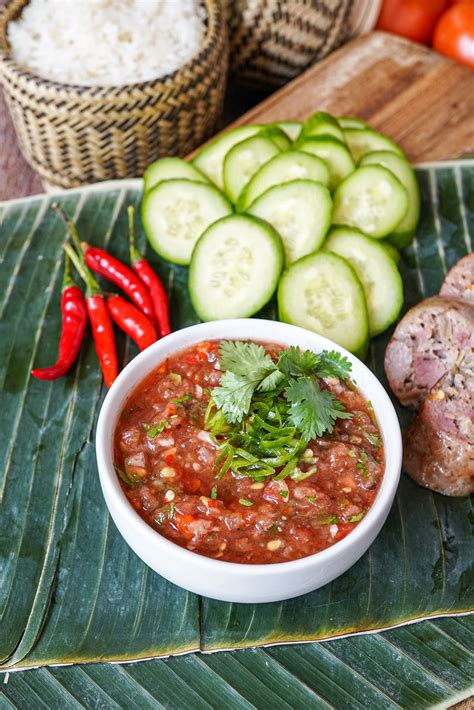 Jeow Mak Len (Lao Tomato Dipping Sauce) in a white bowl next to chilies, cucumber, rice, and ...