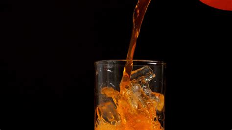 4K Slow motion of orange juice pouring into glass close-up on black ...