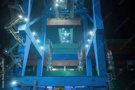 operation of container terminal at night. Unloading container ship at night. Mooring cranes ...