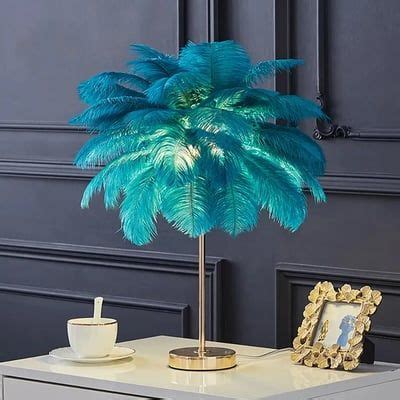 a blue palm tree in a gold vase next to a white table with a cup and ...