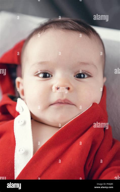 Closeup portrait of cute adorable Caucasian baby boy girl with black brown eyes in red hoodie ...