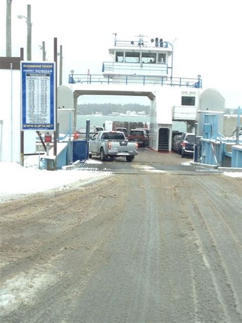 the cars are parked on the side of the road in front of the ferry boat