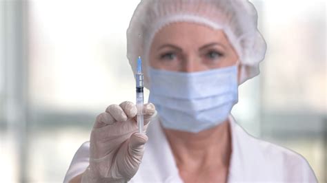 Woman doctor preparing syringe for injection. Female doctor or nurse holding syringe with liquid ...