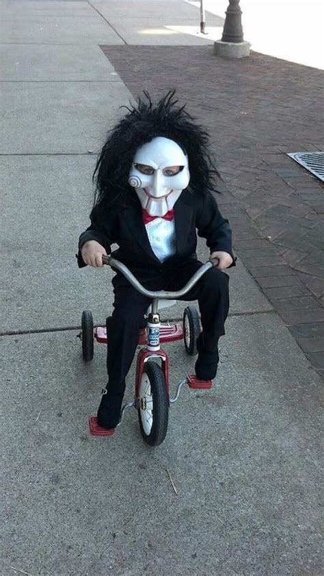 little boy, dressed as jigsaw, saw movie inspired, riding a tricycle ...