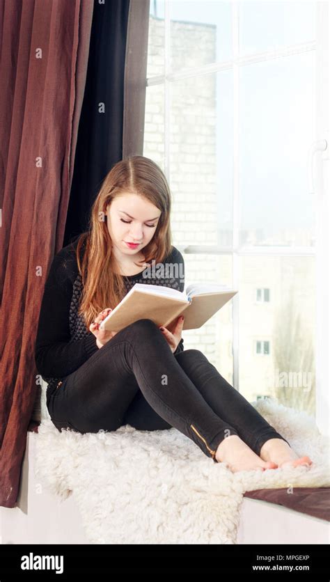 Young girl reading book near the window Stock Photo - Alamy