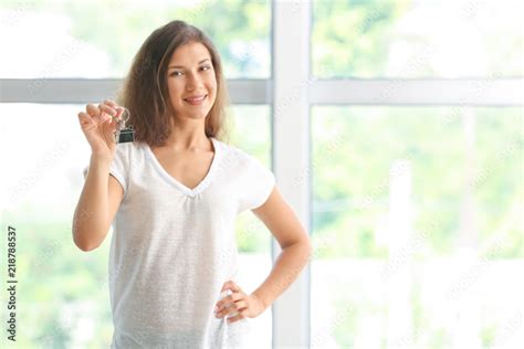 Happy young woman with key from her new house indoors Stock Photo | Adobe Stock