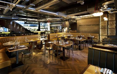 the interior of a restaurant with wooden tables and chairs, wood flooring and exposed lighting