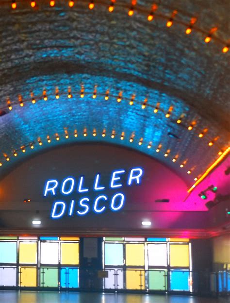 the entrance to roller disco at night with neon lights in the ceiling and large windows