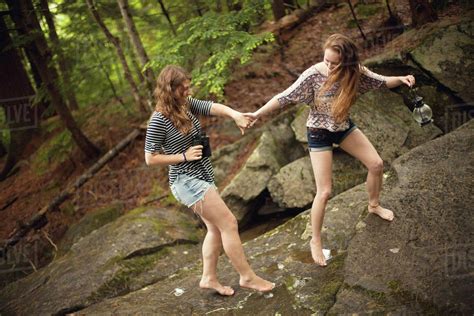 Girls walking barefoot on boulder in forest - Stock Photo - Dissolve