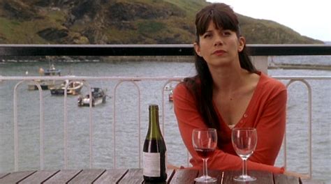 a woman sitting at a table with two wine glasses and bottle in front of her