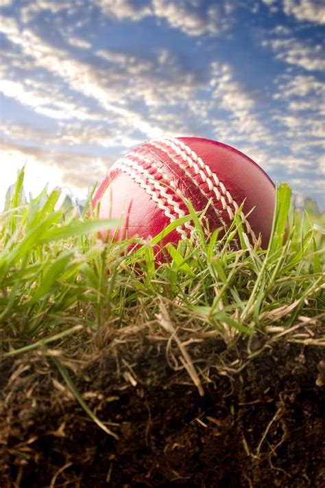 Red Cricket Ball on Grass with Sky Background