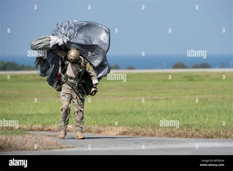 A U.S. Air Force Airman carries parachute gear after conducting a high ...