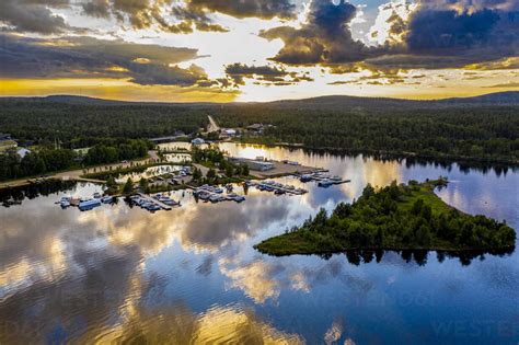 Finland, Lapland, Inari, Aerial view of Lake Inari at dramatic sunset with jetties in background ...