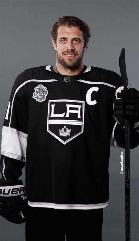 a man in black jersey holding up a hockey stick and wearing an ice ...