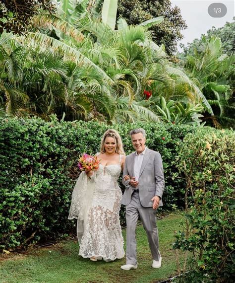 the bride and groom are walking together in front of some bushes with ...