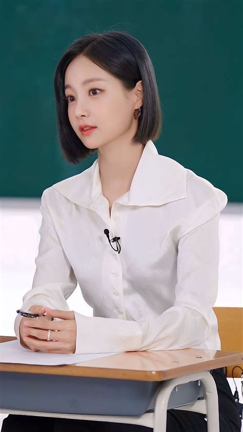 a woman sitting at a desk in front of a blackboard