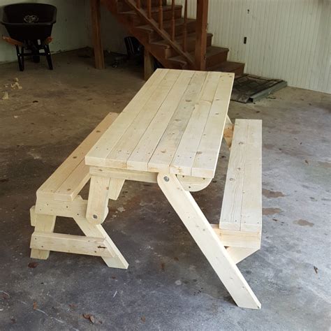 a wooden picnic table sitting in the middle of a room with stairs leading up to it