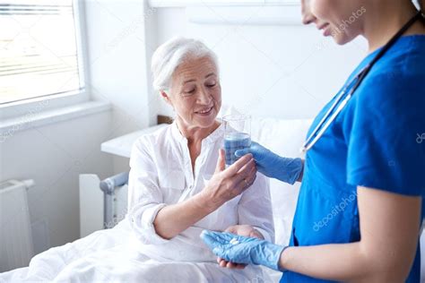 Nurse giving medicine to senior woman at hospital Stock Photo by ©Syda ...