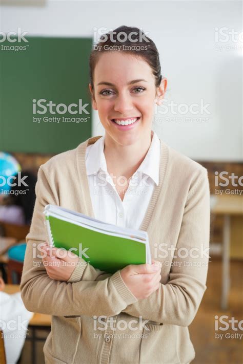 Pretty teacher smiling at camera at back of classroom at the... | Pretty teacher, Teacher, Stock ...