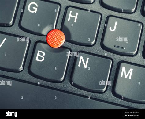 A close-up photo of the red pointing stick of on a laptop keyboard Stock Photo - Alamy