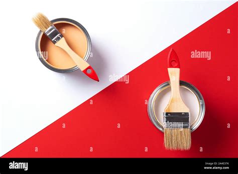 Wooden paint brushes, open paint cans on trendy red and white background. Top view, copy space ...