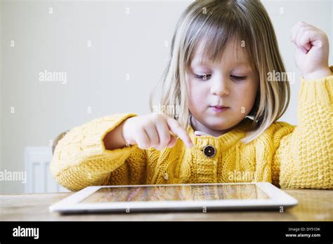 Young girl at kitchen table using digital tablet Stock Photo - Alamy