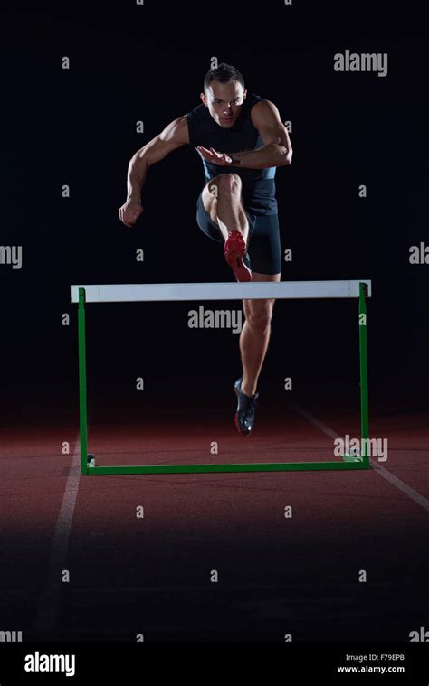 man athlete jumping over a hurdles on athletics race track Stock Photo - Alamy